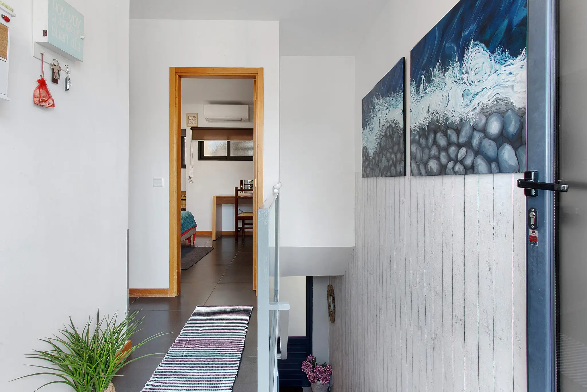 Entrance hall with sea-themed paintings and view into a bedroom
